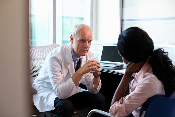Male doctor speaking to female patient